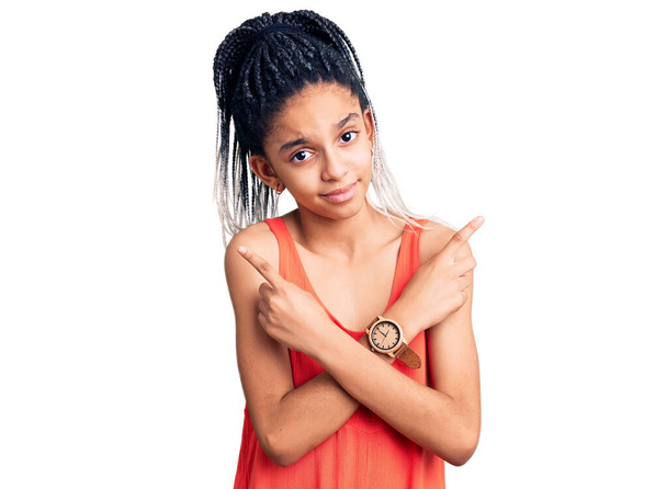 Linda chica afroamericana vistiendo ropa casual apuntando a ambos lados con los dedos, diferente dirección en desacuerdo  - Foto, Imagen