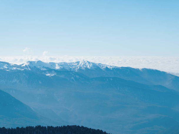 Ορεινή κοιλάδα με χιονισμένες κορυφές και σύννεφα σε επίπεδο κορυφής ενάντια στον καθαρό ουρανό - Φωτογραφία, εικόνα