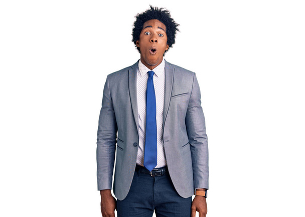 Handsome african american man with afro hair wearing business jacket afraid and shocked with surprise and amazed expression, fear and excited face.  - Photo, Image