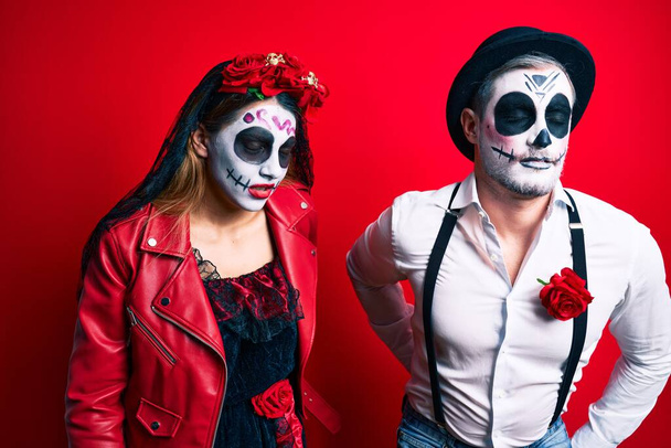 Пара носить день мертвого костюма поверх красных страданий от боли в спине, прикосновение к спине с рукой, мышечная боль  - Фото, изображение