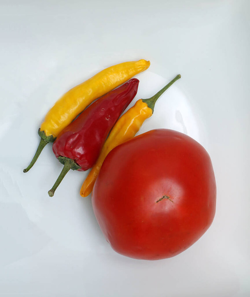 白を背景に黄色と赤のホットスパイシーなピーマンと新鮮な有機トマト - 写真・画像