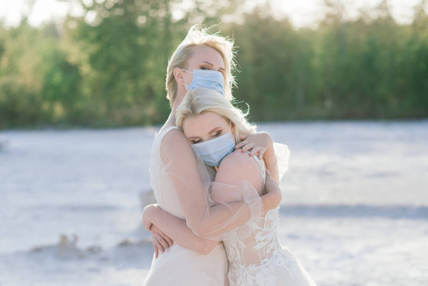 Лесбиянки пара свадьба на белом песке, носить маски, чтобы предотвратить эпидемию COVID-19 - Фото, изображение