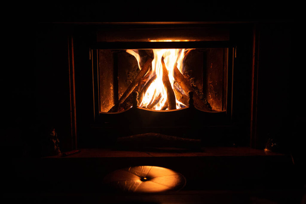 Kamin im Wohnzimmer des Hauses mit einem Hocker und Dekoration. Warme und vertraute Winterszene. - Foto, Bild