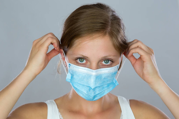 Молода жінка накладає маску на обличчя під час пандемії
. - Фото, зображення