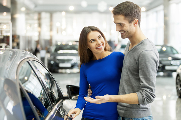 Couple standing at the dealership choosing the car to buy - Фото, изображение