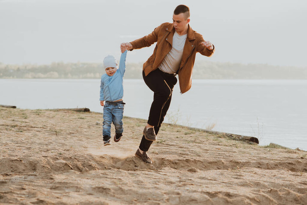 Felice papà e figlio giocano sulla sabbia sulla spiaggia vicino al fiume - Foto, immagini