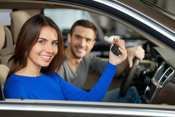 Couple sitting inside of their new car while woman showing keys - Φωτογραφία, εικόνα