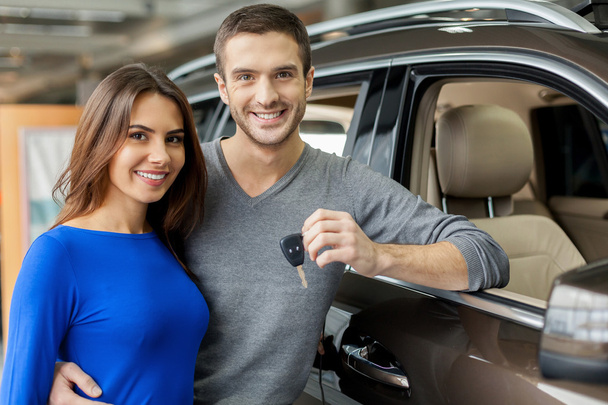 Young men standing near the car, hugging his girlfriend and holding a key - Foto, imagen