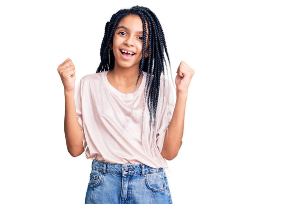 Мила афроамериканська дівчина, одягнена в повсякденний одяг, що кричить гордо, відзначаючи перемогу і успіх, дуже захоплений піднятими руками.  - Фото, зображення