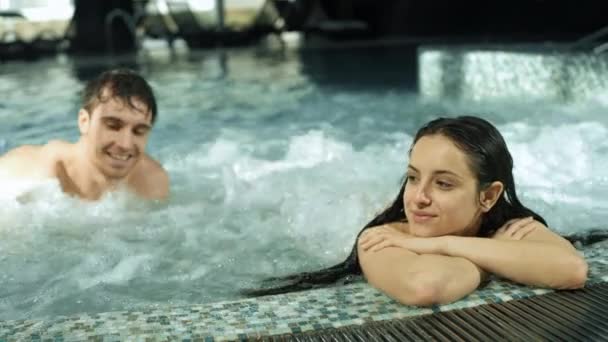 Reunião de casal bonita na piscina de spa. Guy e menina relaxante em hidromassagem dentro - Filmagem, Vídeo