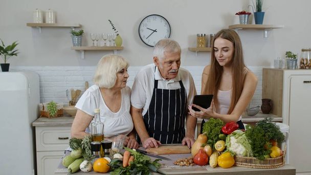 Vanhempi mies ja nainen kuuntelee resepti tyttö digitaalinen tabletti terveellistä ruokaa ravitsemus - Valokuva, kuva