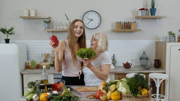 Η γιαγιά με την εγγονή της συστήνουν να τρώνε ωμά λαχανικά. Διατροφή των λαχανικών - Φωτογραφία, εικόνα
