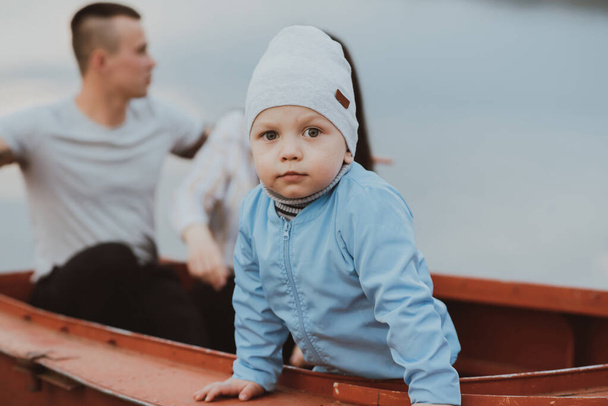 young son and a happy couple of parents sit in a boat - Photo, Image