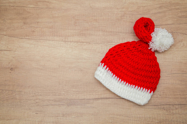 κόκκινο καπέλο santa claus σε ανοιχτό ξύλινο φόντο. Πρωτοχρονιά. Άποψη από ψηλά - Φωτογραφία, εικόνα