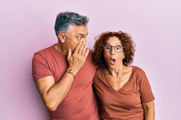 Beautiful middle age couple together wearing casual clothes hand on mouth telling secret rumor, whispering malicious talk conversation  - Photo, Image