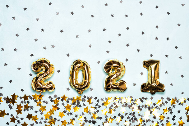 2021 Luftballons mit schwarz-goldenen Sternen und Kreis-Konfetti auf blauem Hintergrund. Weihnachts- oder Neujahrskonzept. Draufsicht und flache Lage. - Foto, Bild