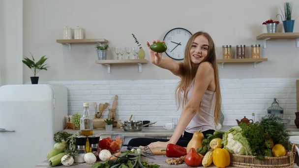 Girl recommending eating raw vegetable food. Showing avocado in hands. Weight loss and diet concept - Zdjęcie, obraz