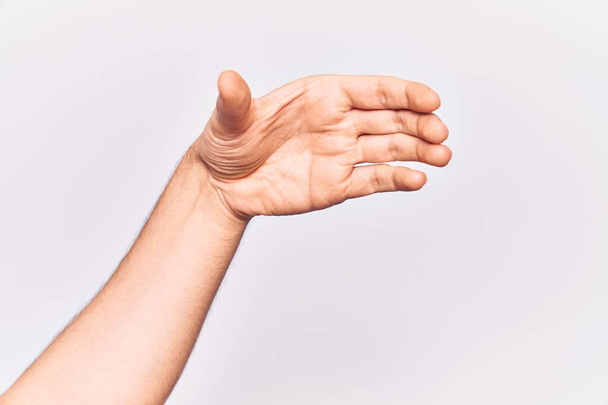 Primer plano de la mano de un joven caucásico sobre un fondo aislado sosteniendo un objeto invisible, una mano vacía cortando y agarrando un gesto  - Foto, imagen