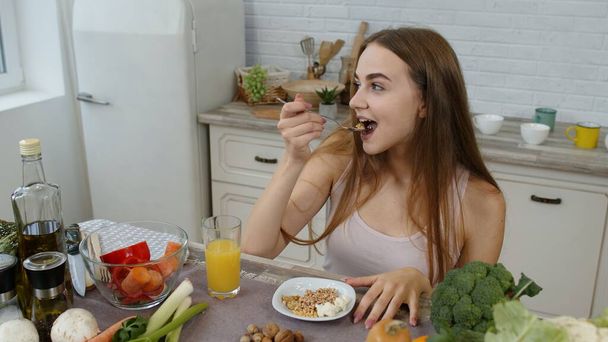 Bella ragazza mangiare germogli crudi grano saraceno con noci in cucina con verdure fresche e frutta - Foto, immagini