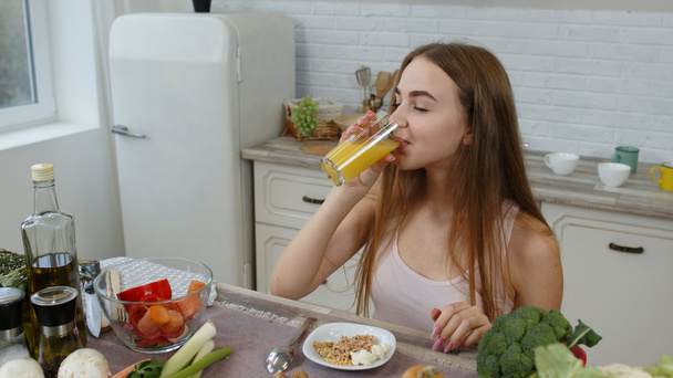 Girl eating raw sprouts buckwheat with nuts, drinking orange juice in kitchen. Weight loss and diet - Фото, зображення