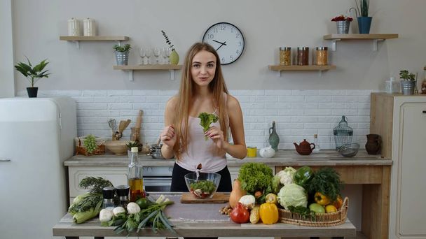 Jeune fille dansant, s'amuser et cuisiner une salade avec des légumes crus. Jeter des morceaux de laitue - Photo, image