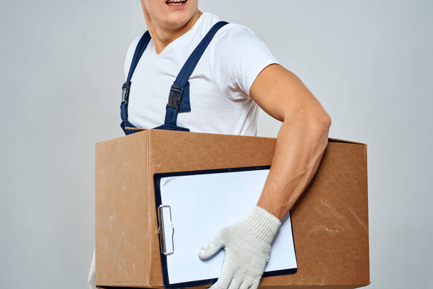 Homme travailleur avec boîte dans les mains livraison chargement service lumière arrière-plan - Photo, image