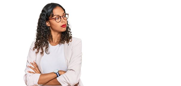 Young african american girl wearing business clothes looking to the side with arms crossed convinced and confident  - Photo, Image