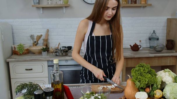 Veganistische vrouw op zoek naar culinair recept online op mobiele telefoon. Kooksalade met rauwe groenten - Foto, afbeelding