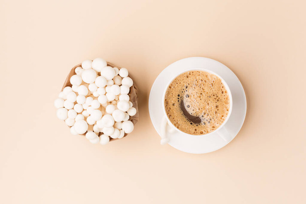 Fresh shimeji (white beech) mushrooms on pastel beige paper background. Superfood Trend fresh mushrooms and cup of coffee. Top view, copy space. - 写真・画像