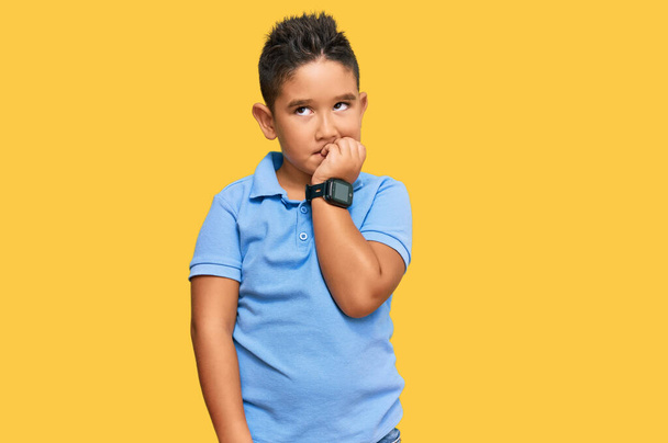 小さな男の子のヒスパニック系の子供は、口の爪をかむ上で手でストレスと緊張して見えるカジュアルな服を着て。不安の問題.  - 写真・画像