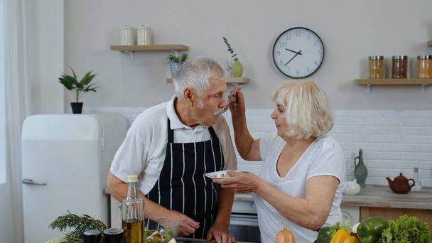 Senior vrouw voedt man met rauwe spruiten boekweit met noten. Eco-voedsel eten dieet. Wereld veganistische dag - Foto, afbeelding