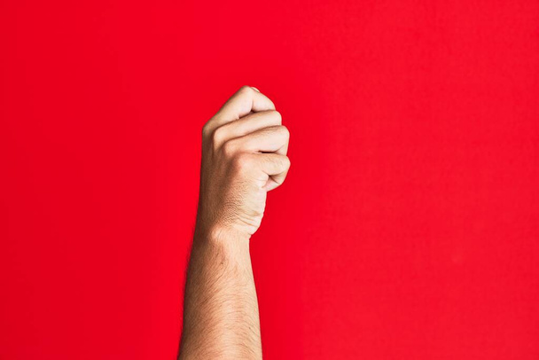 Arm of caucasian white young man over red isolated background holding blank space with thumb finger, business and advertising  - Photo, Image