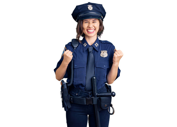 Young beautiful girl wearing police uniform excited for success with arms raised and eyes closed celebrating victory smiling. winner concept.  - Foto, imagen