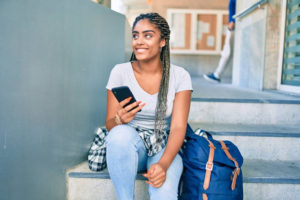 Fiatal afro-amerikai diák nő mosolyog boldog segítségével okostelefon az egyetemi campus - Fotó, kép