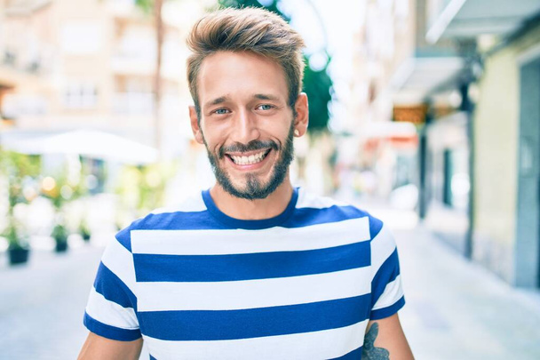 Schöner kaukasischer Mann mit Bart, der im Freien glücklich lächelt - Foto, Bild