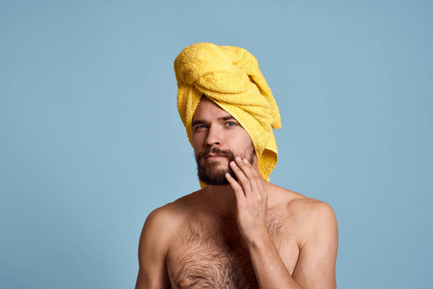 férfi sárga törölköző a fejen tiszta bőr csupasz vállak kék háttér - Fotó, kép