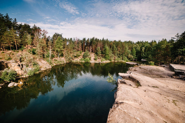 Landscape of an old flooded industrial granite quarry filled with water. Lake on the background of rocks and fir trees. Canyon. The nature of autumn. Place for text and design. - 写真・画像
