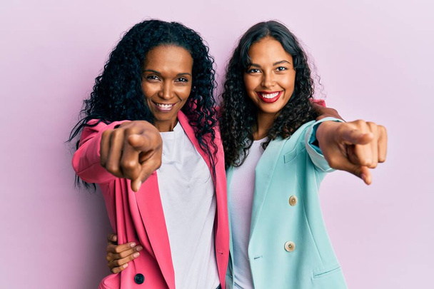Mère et fille afro-américaine portant un style d'affaires pointant vers vous et la caméra avec les doigts, souriant positif et joyeux  - Photo, image