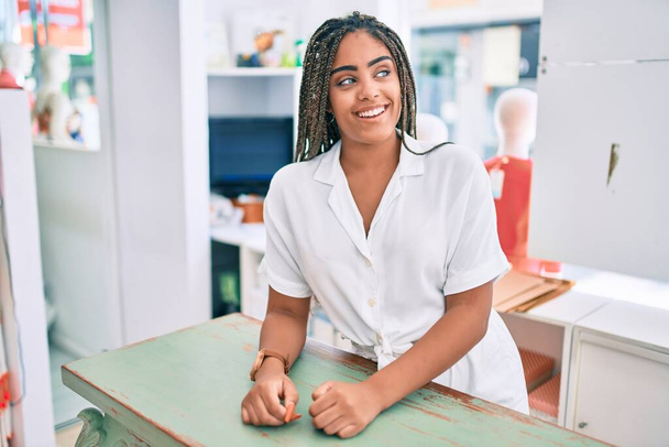 Νεαρή Αφρικάνα Αμερικανίδα χαμογελαστή χαρούμενη που δουλεύει στο κατάστημα λιανικής πώλησης. - Φωτογραφία, εικόνα