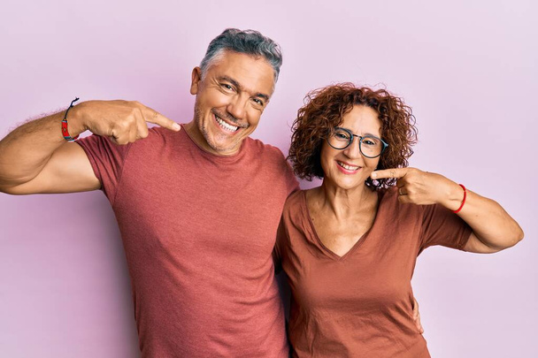 Beautiful middle age couple together wearing casual clothes smiling cheerful showing and pointing with fingers teeth and mouth. dental health concept.  - Photo, Image