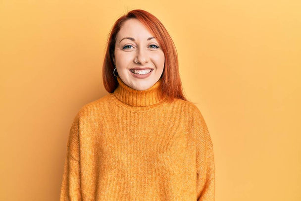 Bella donna rossa che indossa maglione invernale casual su sfondo giallo con un sorriso felice e fresco sul viso. persona fortunata.  - Foto, immagini
