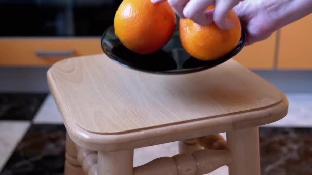 Помістіть тарілку з трьох апельсинів на стілець або табурет. Домашня кухня. Крупним планом
 - Кадри, відео