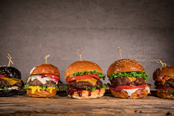 Tasty burgers on wooden table. - Фото, зображення