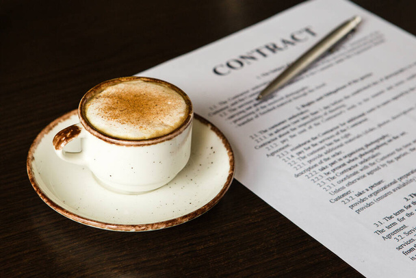 cup of coffee, ballpoint pen, blank contract on a wooden background. Business concept. - Photo, Image