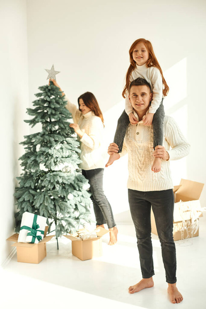 Happy family decorating the Christmas tree at home - Valokuva, kuva