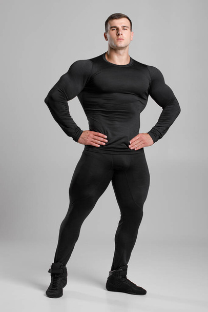 Muscular man in black compression sportswear on gray background - 写真・画像
