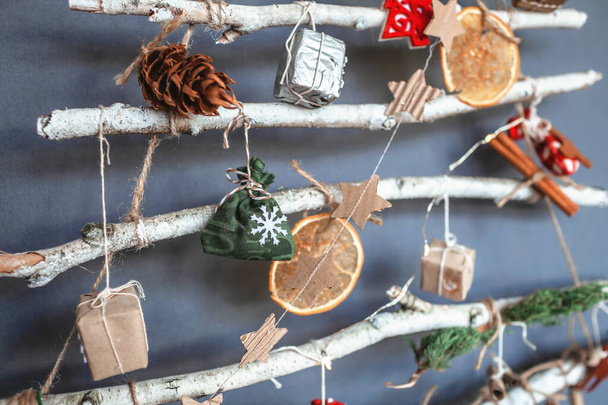 Originální alternativní vánoční stromeček se zamrzlými větvemi a zdobený drobnými ekologickými hračkami a papírovými věnci, prázdninami bez odpadu, nulovým odpadem a prázdninami bez plastů - Fotografie, Obrázek