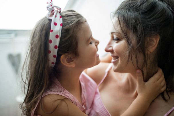 Mother and small daughter indoors at home, hugging. - Foto, Bild