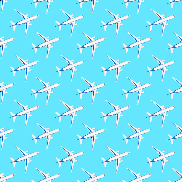 Naadloos patroon met wit vliegtuig op blauwe achtergrond. Repetitieve reisdruk voor papier, stof of behang. Speelgoedvliegtuig van boven. Reizen en vooruitgang concept plat lay - Foto, afbeelding