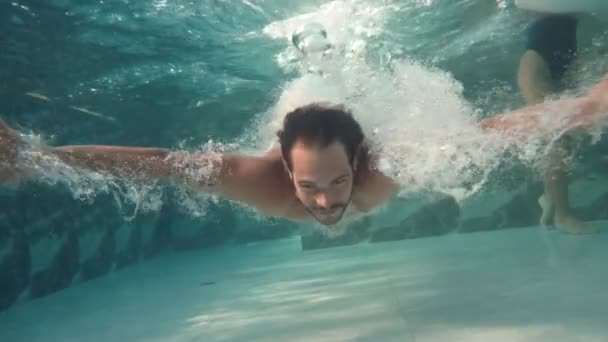 Baixo ângulo de tiro subaquático de homem apto mergulho em água transparente no resort - Filmagem, Vídeo